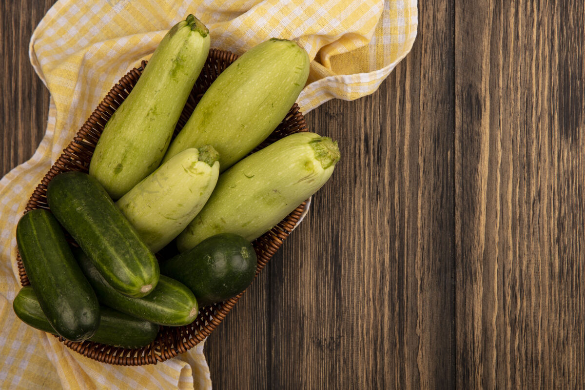 蔬菜顶视图新鲜的绿色蔬菜 如黄瓜和西葫芦在一个黄色格子布木桶表面复制空间食品衣服配料