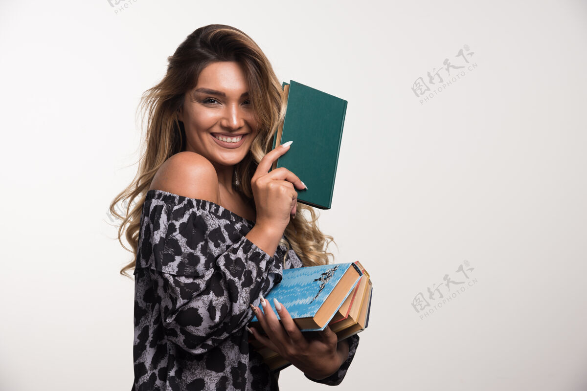 人年轻女子拿着书在白墙上笑女人年轻聪明