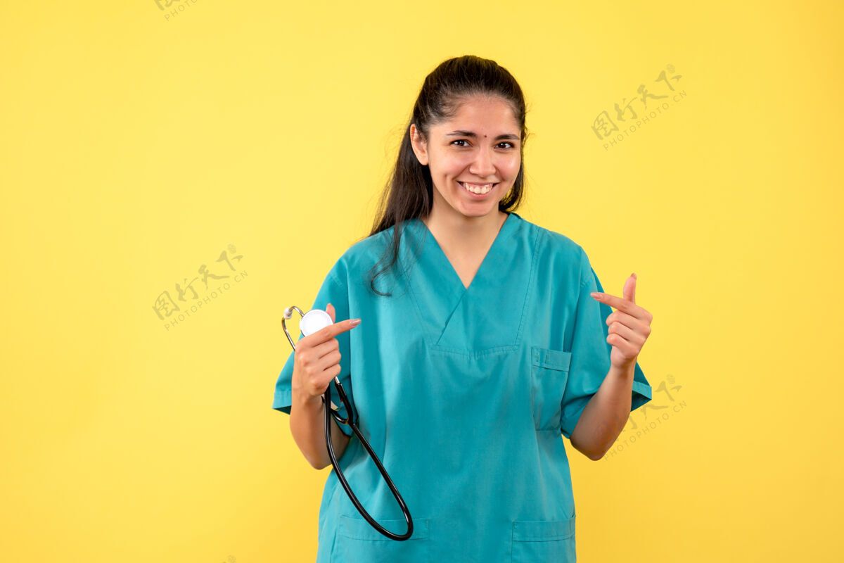 听诊器正面图黄色背景上 笑着的女医生手里拿着听诊器人护士手
