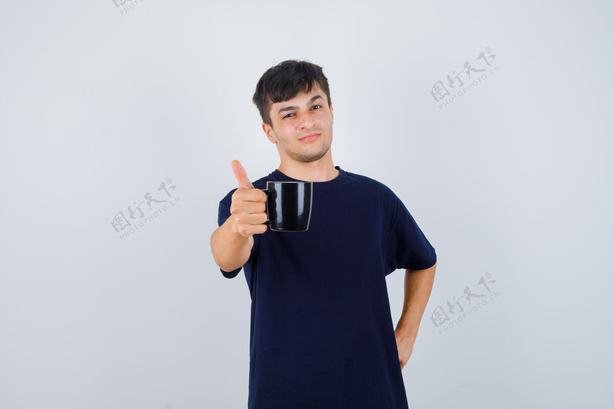 时尚年轻人提供一杯咖啡在黑色t恤衫 并期待自豪前视图微笑杯子男人