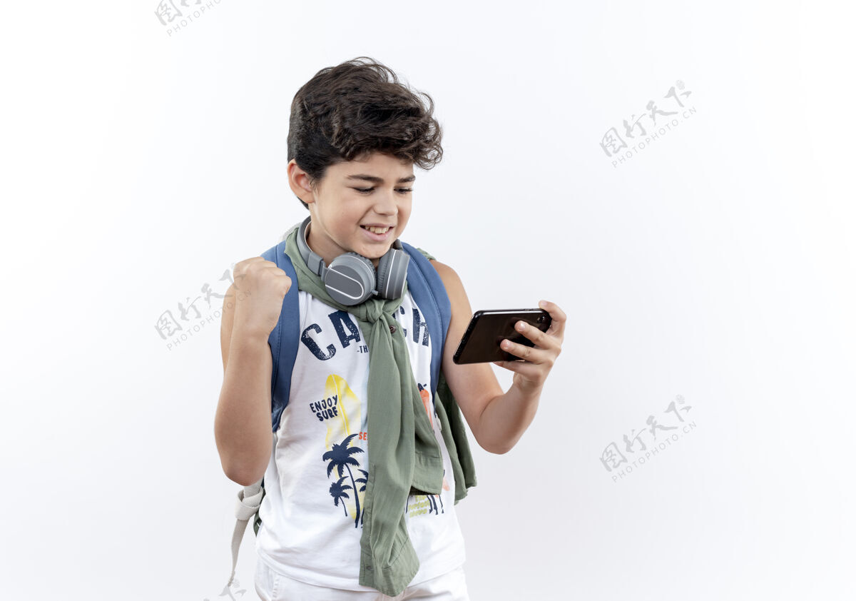 小学生快乐的小男孩戴着背包和耳机打电话 显示是的手势电话表演玩