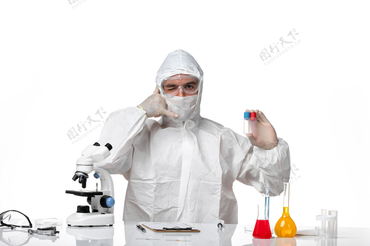 到期正面图：男医生穿着防护服 戴着面罩 因为covid拿着烧瓶在浅白色的空间里专业大流行医学