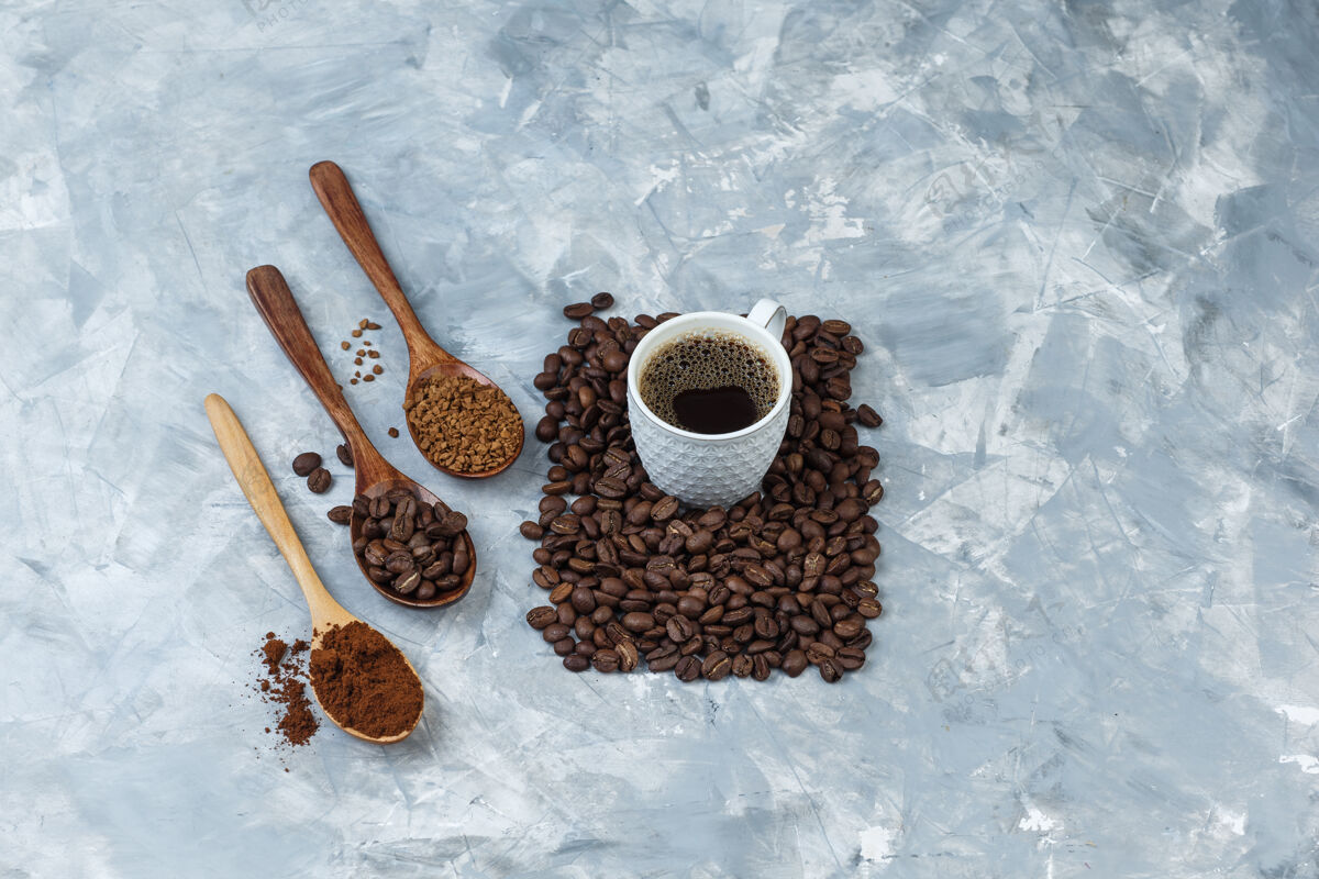 热一套咖啡豆 速溶咖啡 咖啡粉在木制勺子和咖啡杯浅蓝色大理石背景特写泡沫速溶早晨