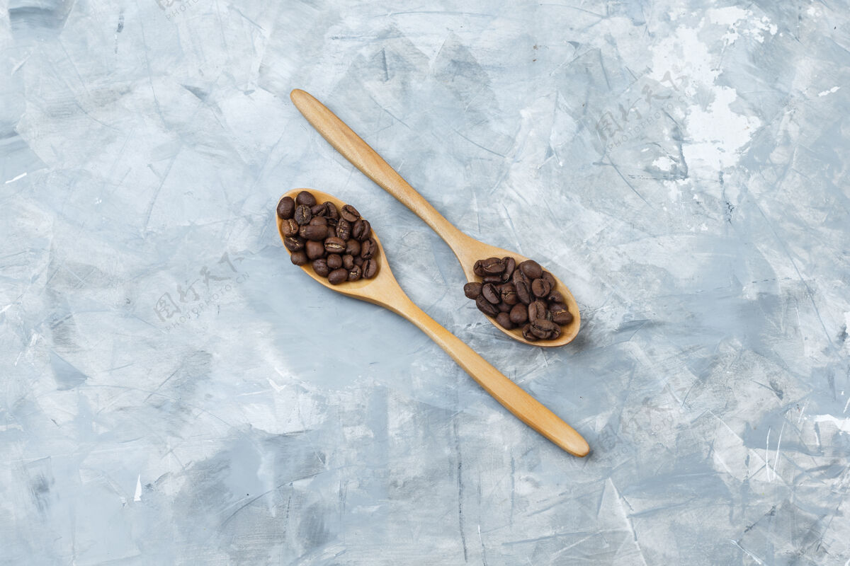 豆类一些咖啡豆放在灰色灰泥背景的木勺里 平放着新鲜的阿拉比卡咖啡