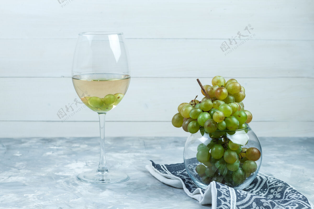 葡萄酒侧视图绿色葡萄在玻璃罐与一杯葡萄酒 厨房毛巾在木制和肮脏的灰色背景水平成熟自然树枝