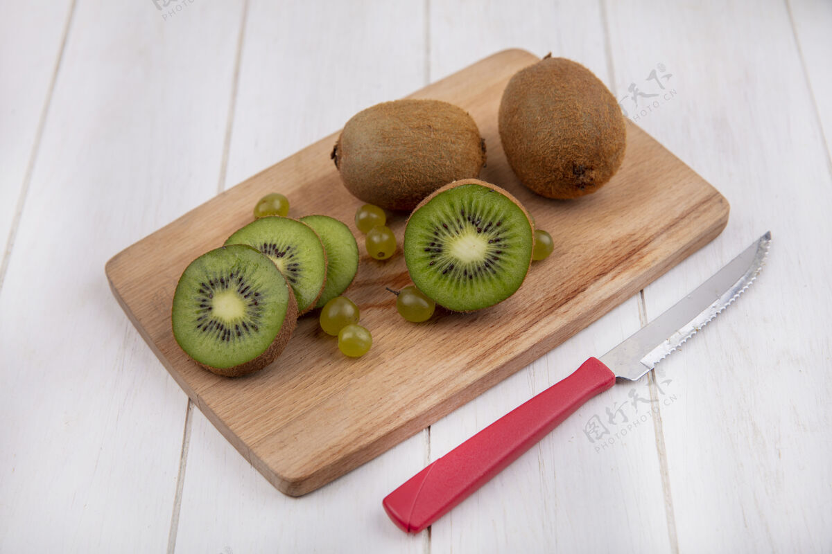 切侧视图猕猴桃在切菜板上与一把刀在一个白色的墙壁刀视野板