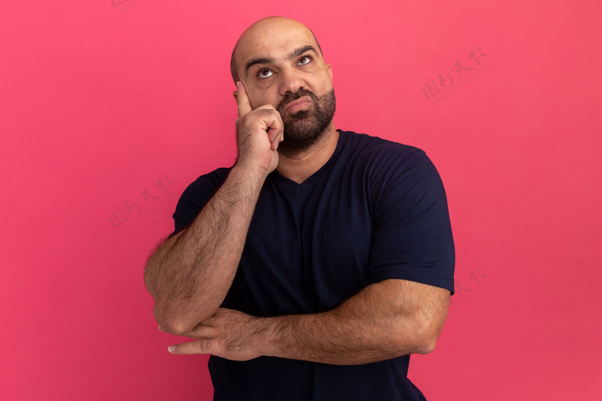 拼图穿着海军t恤的留胡子男人站在粉红色的墙上 困惑地抬头看伙计站起来胡子