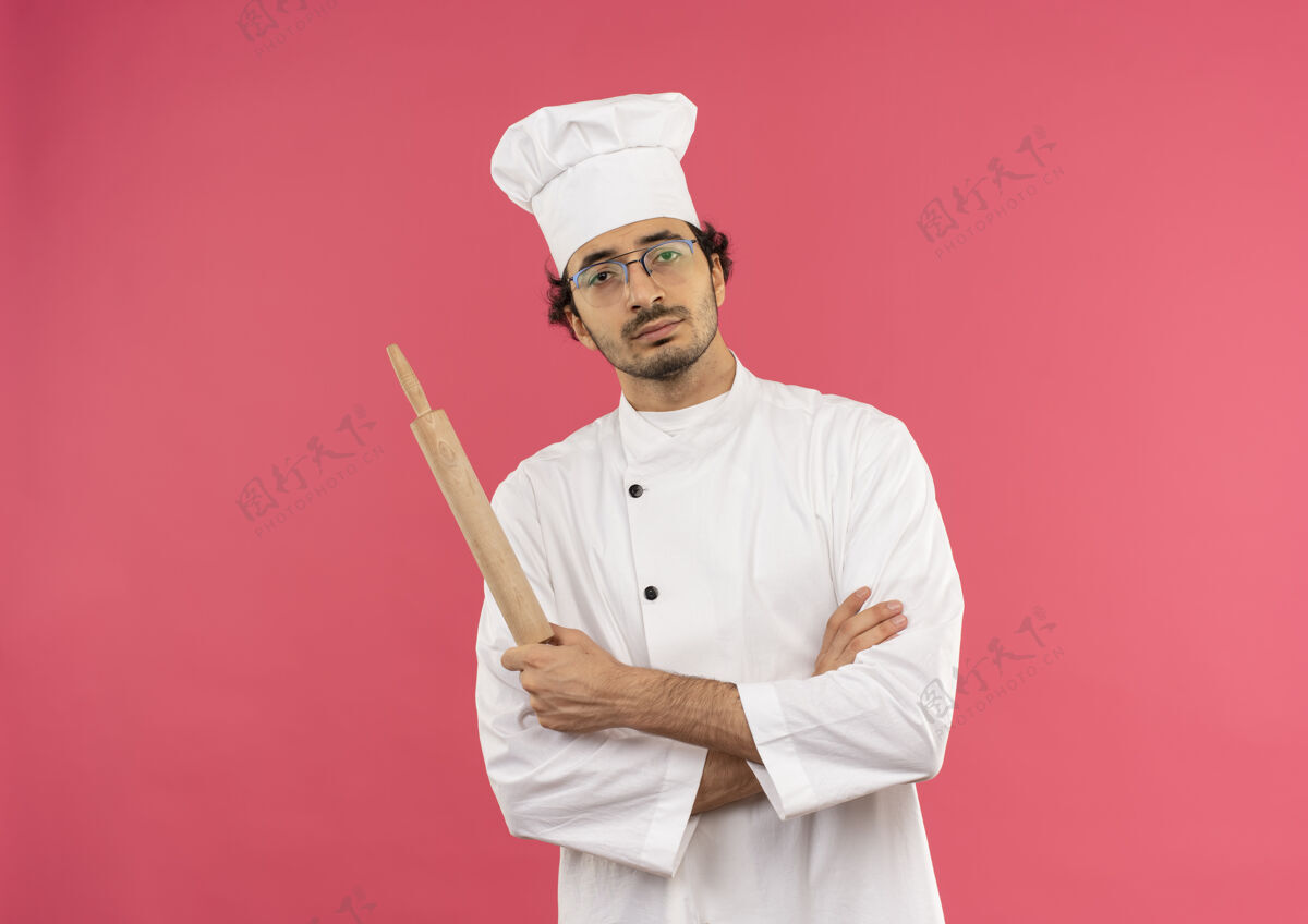 手自信的年轻男厨师穿着厨师制服 戴着眼镜 双手交叉 手持擀面杖眼镜自信交叉