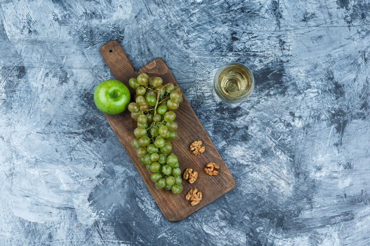 自然俯视图：白葡萄 核桃 苹果放在砧板上 威士忌放在深蓝色大理石背景上水平苹果夏天多汁