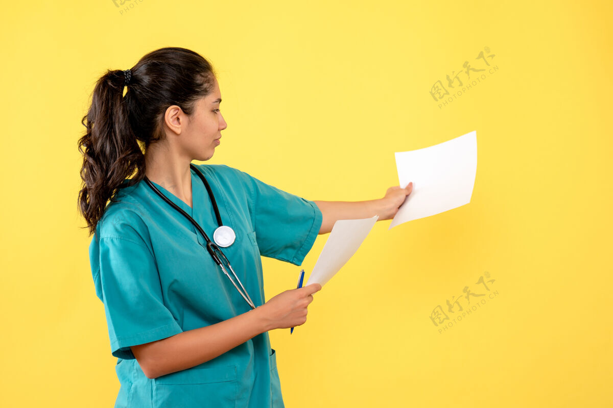 人身穿制服的年轻女医生正看黄色墙上的文件人前台医学