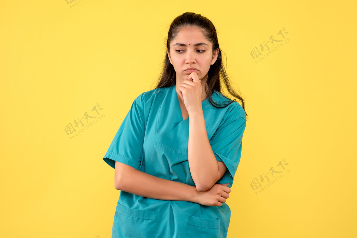 女士美丽的女医生在黄墙上思考的正面图站模型前面
