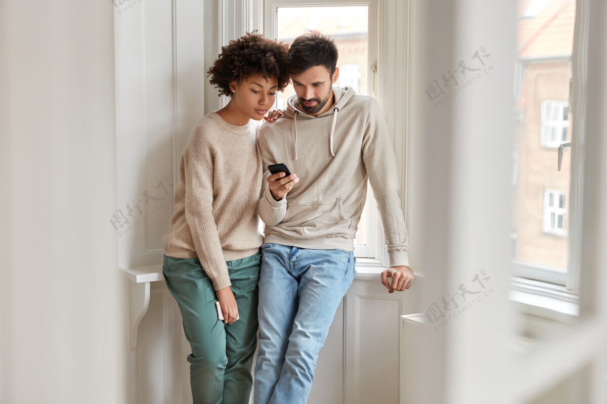 女性室内拍摄混血男女朋友通过手机在线观看视频设备在线窗口