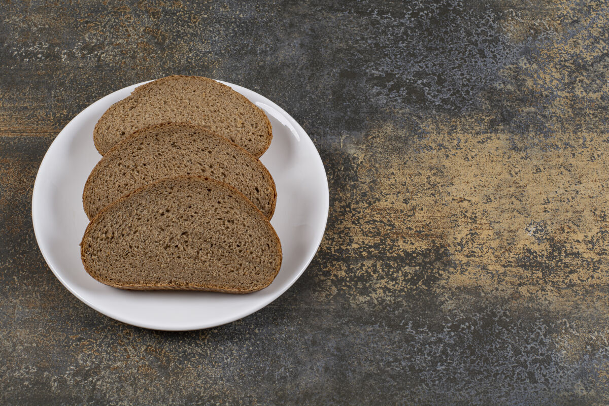 黑麦黑麦黑面包片放在白盘子里面包早餐烘焙