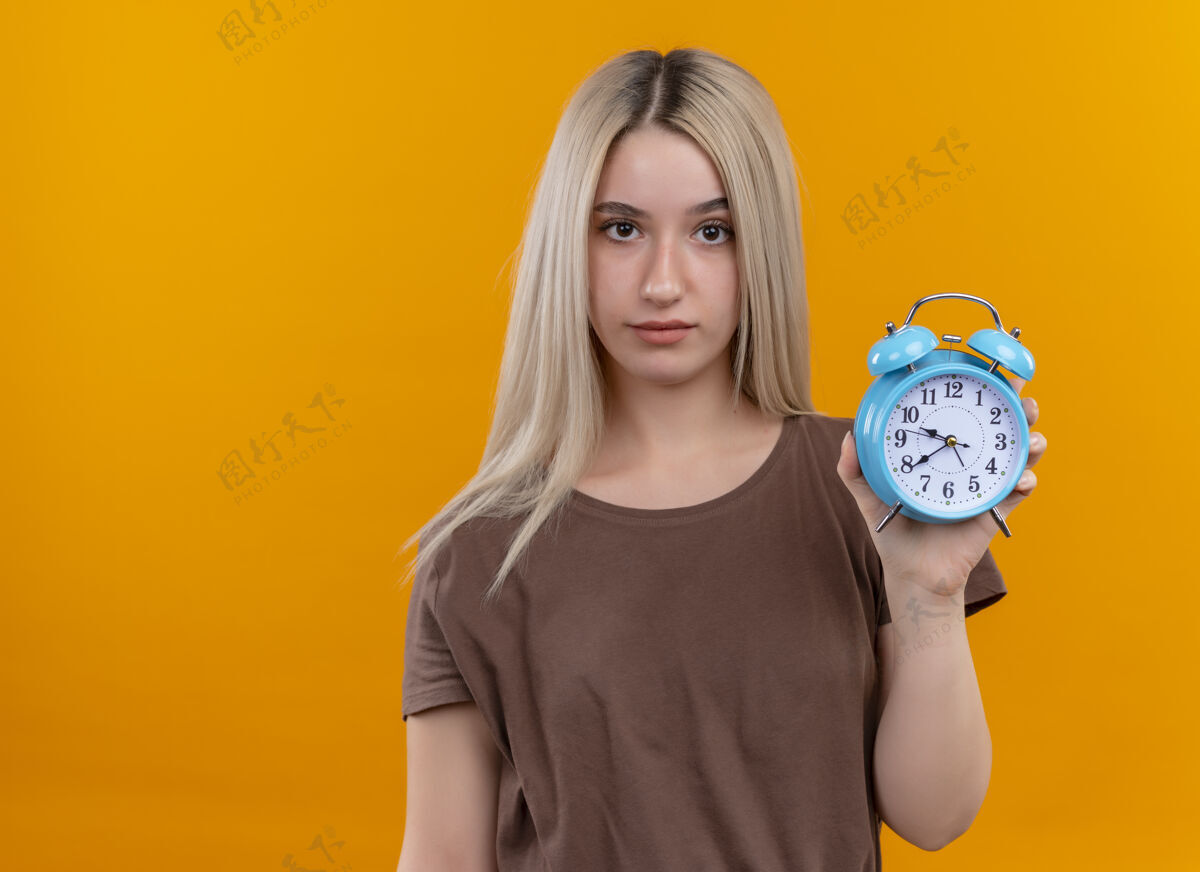 年轻年轻的金发女孩拿着闹钟在孤立的橙色墙上复制空间女孩女人金发