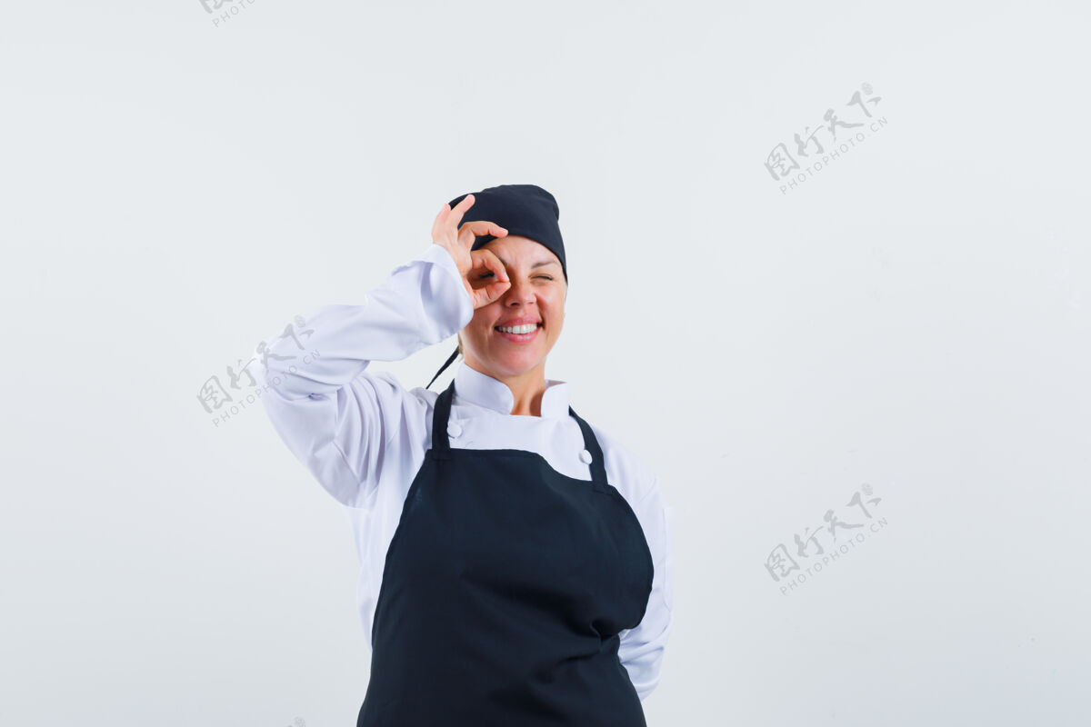 成人女厨师穿着制服 围裙 眼睛上显示ok标志 看起来很开心正视图快乐自信优雅