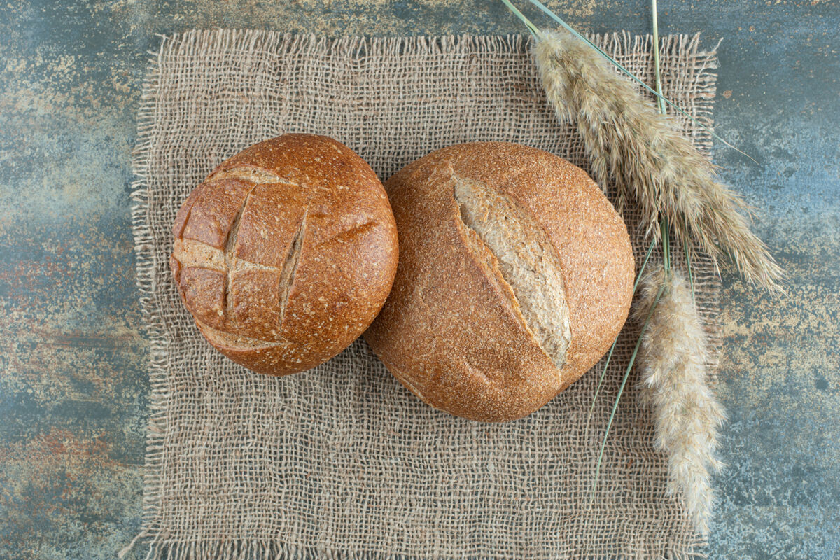 食品两个新鲜的棕色面包和麻布上的小麦小面包新鲜美味