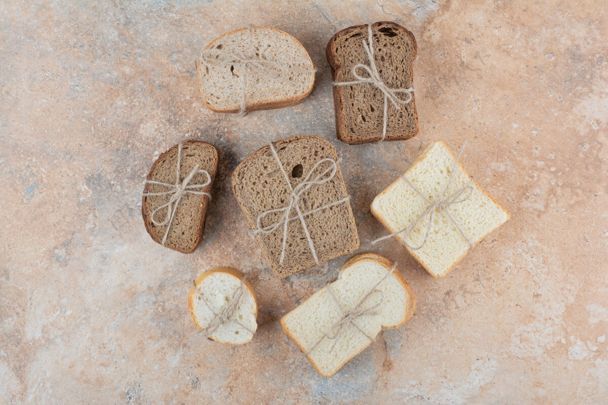 领带各种各样的面包堆在大理石背景上绳索面包切片