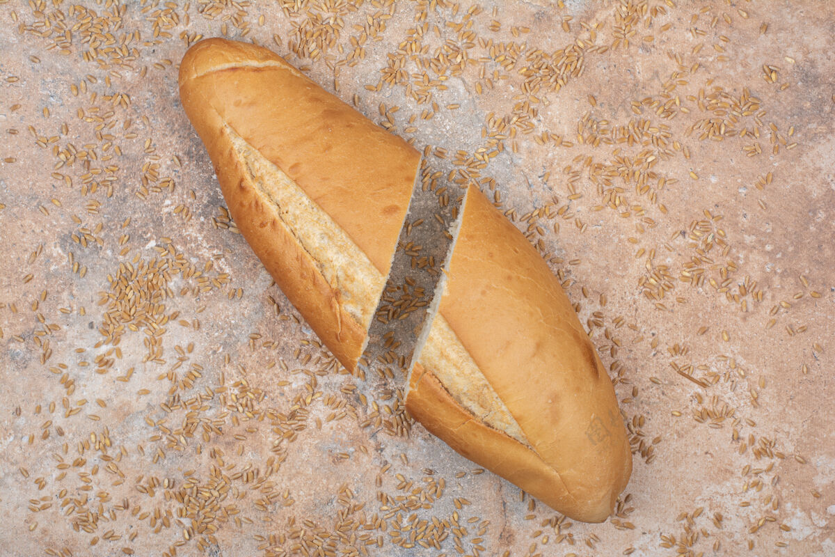 新鲜半切小麦面包和大麦在大理石表面面包食品一半