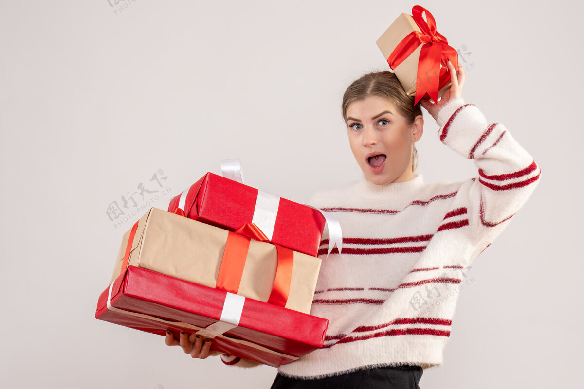 观赏年轻的女性手持圣诞礼物在白色欢乐圣诞节购物