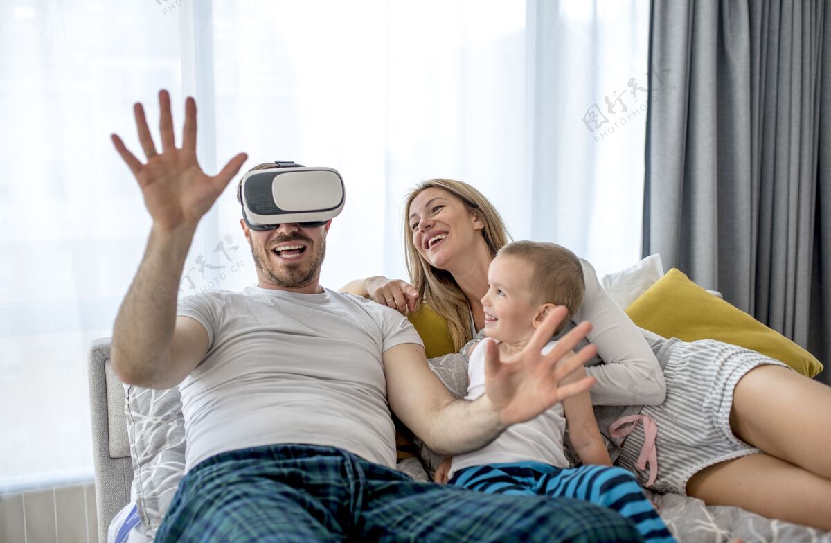 家庭一对夫妇和他们的孩子躺在一起 用虚拟现实耳机看东西快乐债券设备
