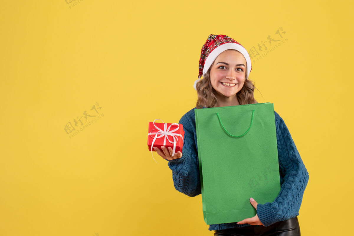 包装年轻的女性拿着包裹和黄色的小礼物观点帽子举行