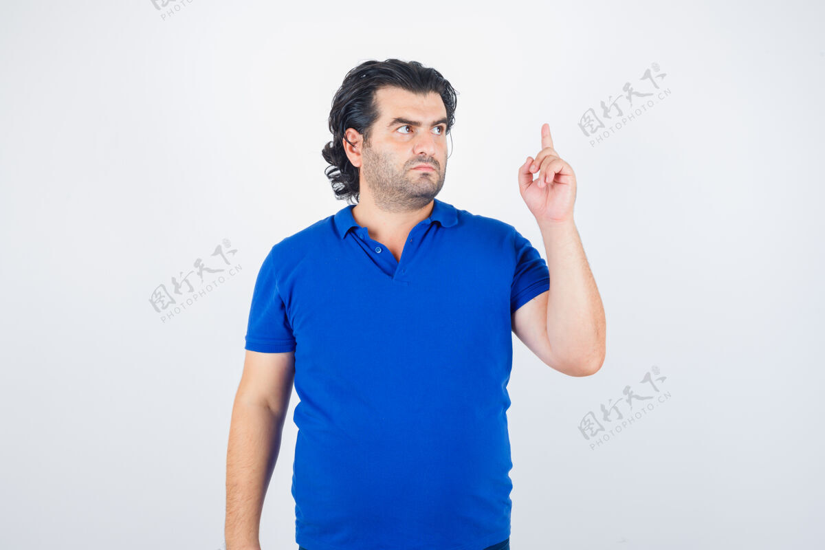 提高成熟男人举起食指在尤里卡手势在蓝色t恤 牛仔裤和看起来理智 前视图浪漫服装敏感