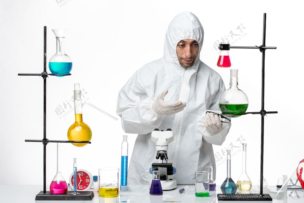 人正面图穿着特殊防护服的男科学家站在桌子周围 拿着解决方案技术人员实验室特殊