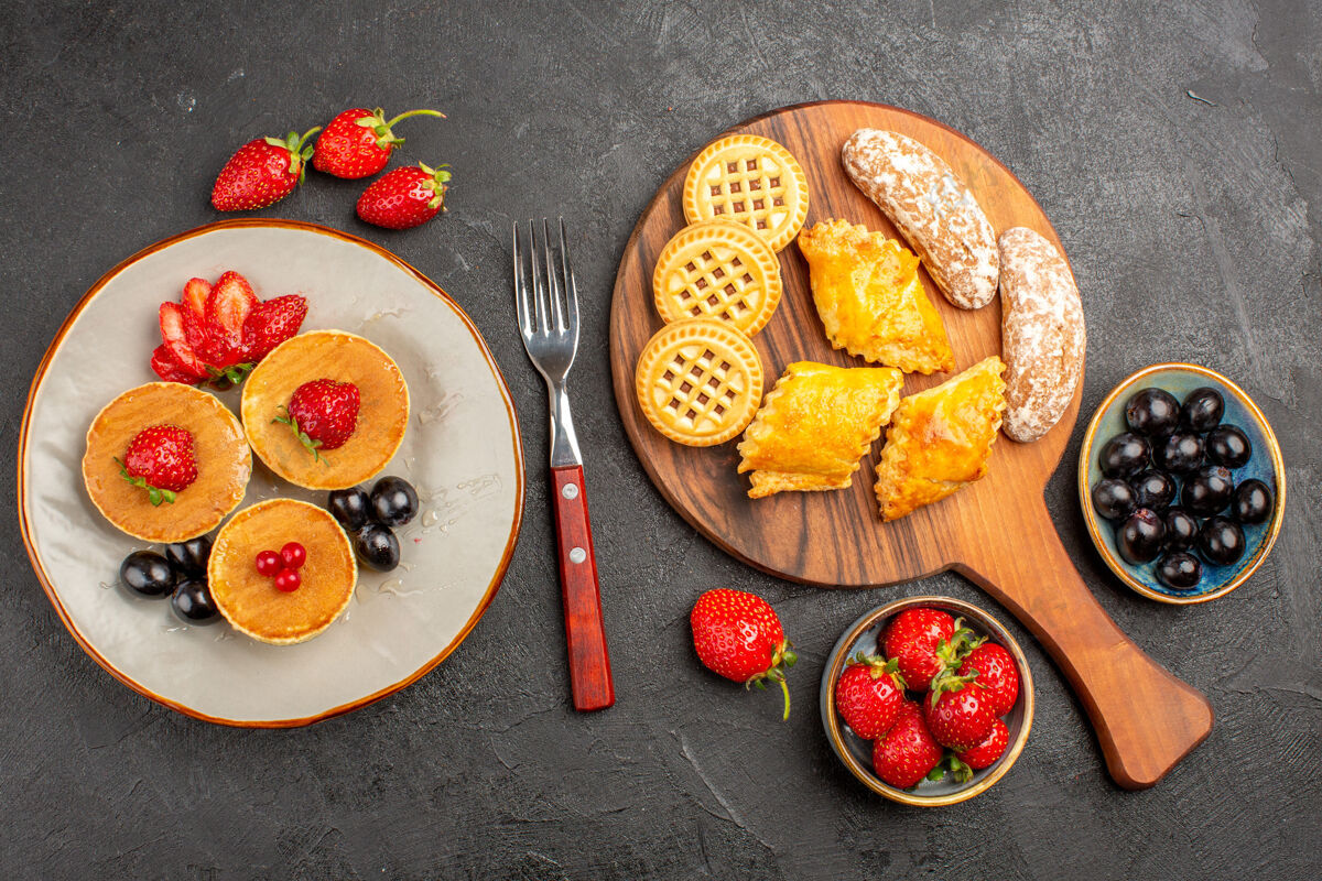 盘子俯瞰美味的薄饼与水果和饼干在黑暗的表面蛋糕水果甜馅饼午餐美味美食