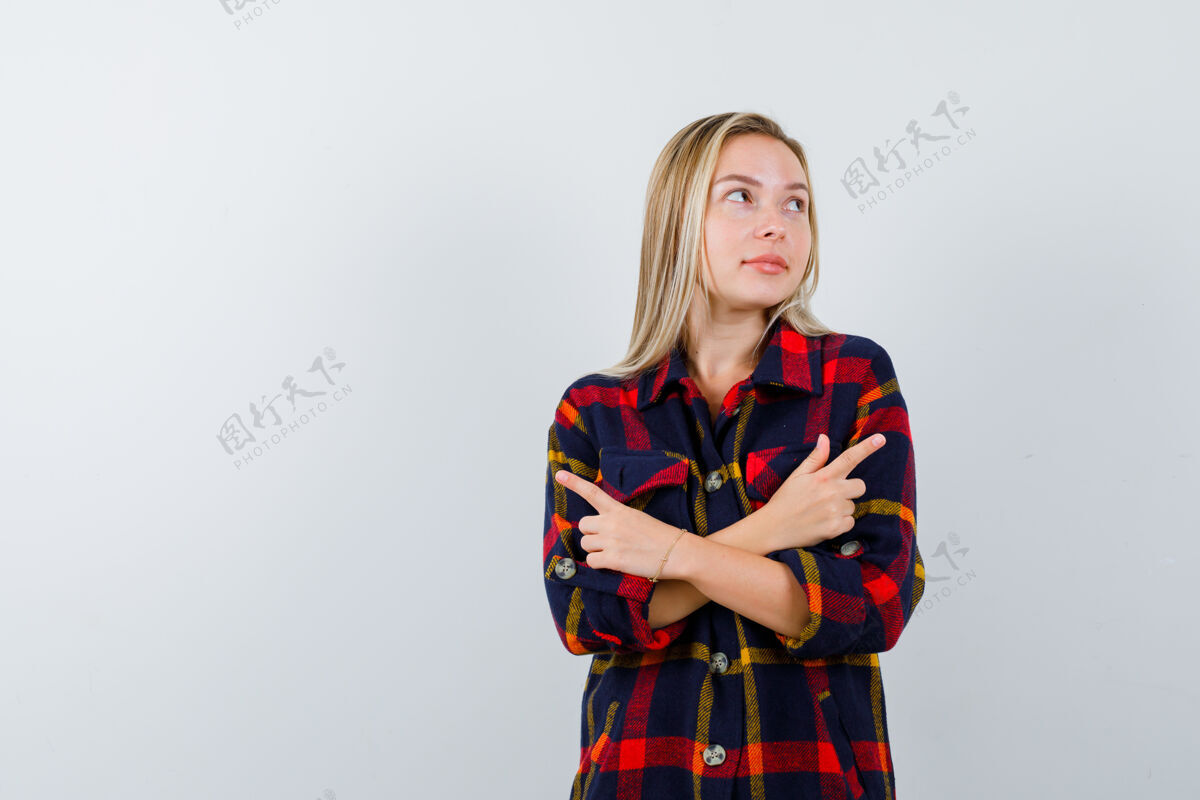 皮肤护理照片中的年轻女士穿着格子衬衫 指着两边 看着犹豫不决的前视图人壁板衬衫