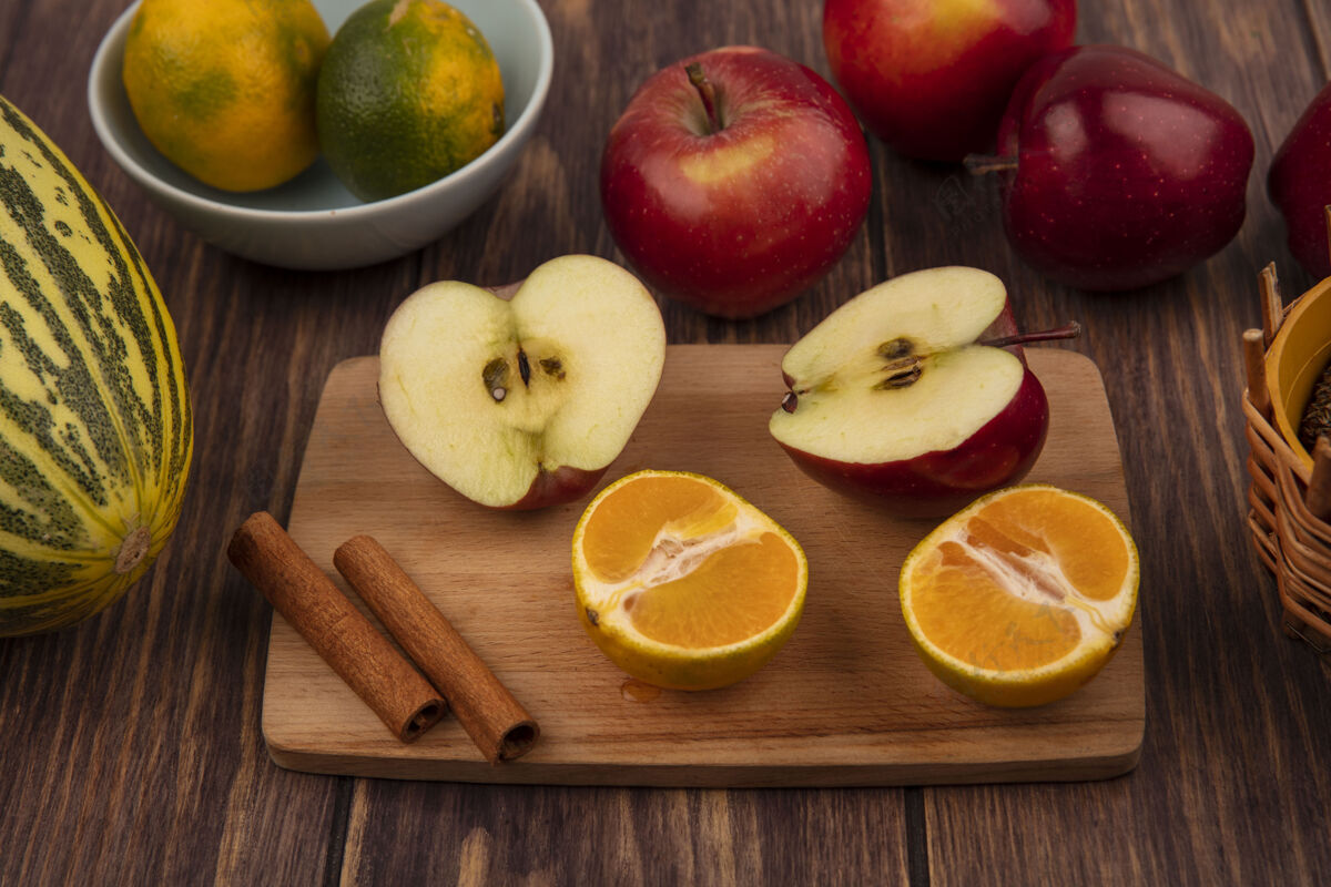 美味半美味的苹果在木制厨房板上的俯视图 有半个橘子和肉桂棒 还有哈密瓜 苹果被隔离在木墙上中心景观顶部