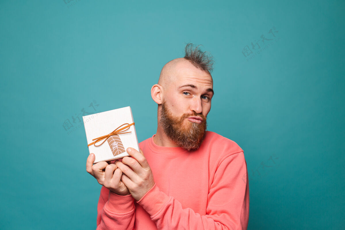快乐留着胡须的欧洲男人在随意的桃花孤零零中 兴奋的兴高采烈地捧着礼盒庆祝惊喜礼物盒