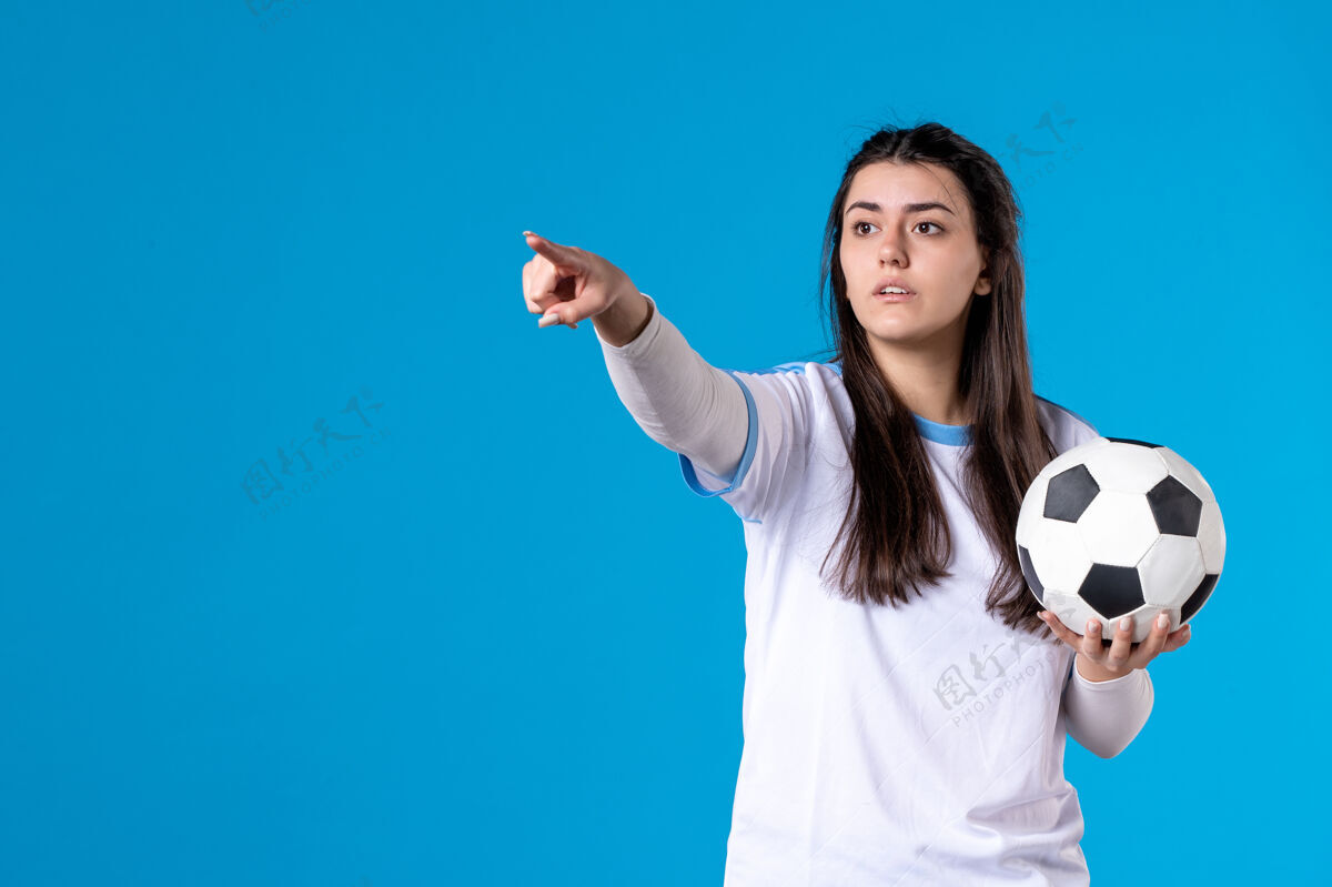 肖像前视图：蓝色墙上有足球的年轻女性视图年轻女性年轻人