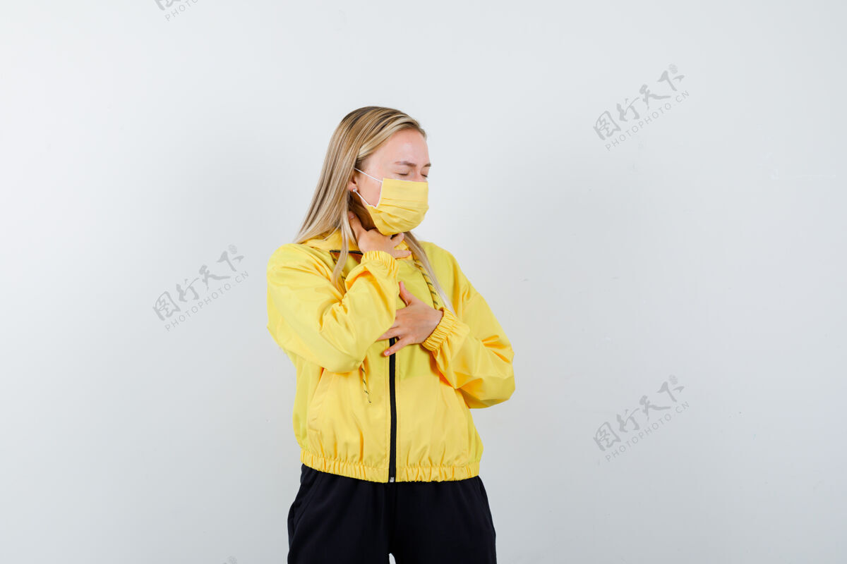 女人穿着运动服的金发女士 戴着口罩 喉咙痛 看起来很不舒服 正视图生病年轻喉咙