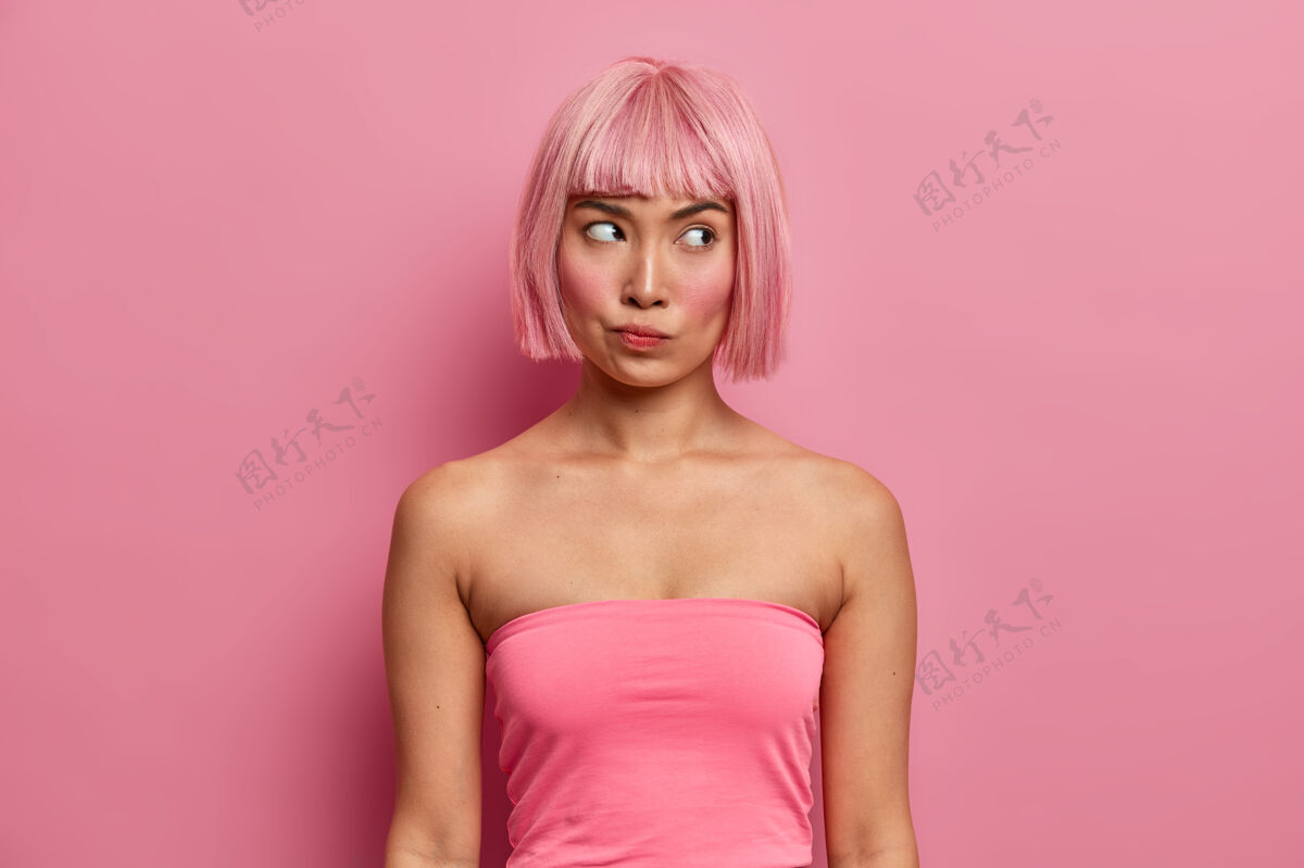 粉色头发一张严重不满的女人的照片 梳着鲍勃的发型 穿着粉色上衣 沉思着 认真地思考着提议 想办法如何解决麻烦 思考决定女性人姿势