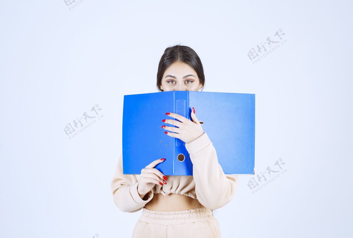 人新来的助手把脸藏在蓝色文件夹后面模特人类女人