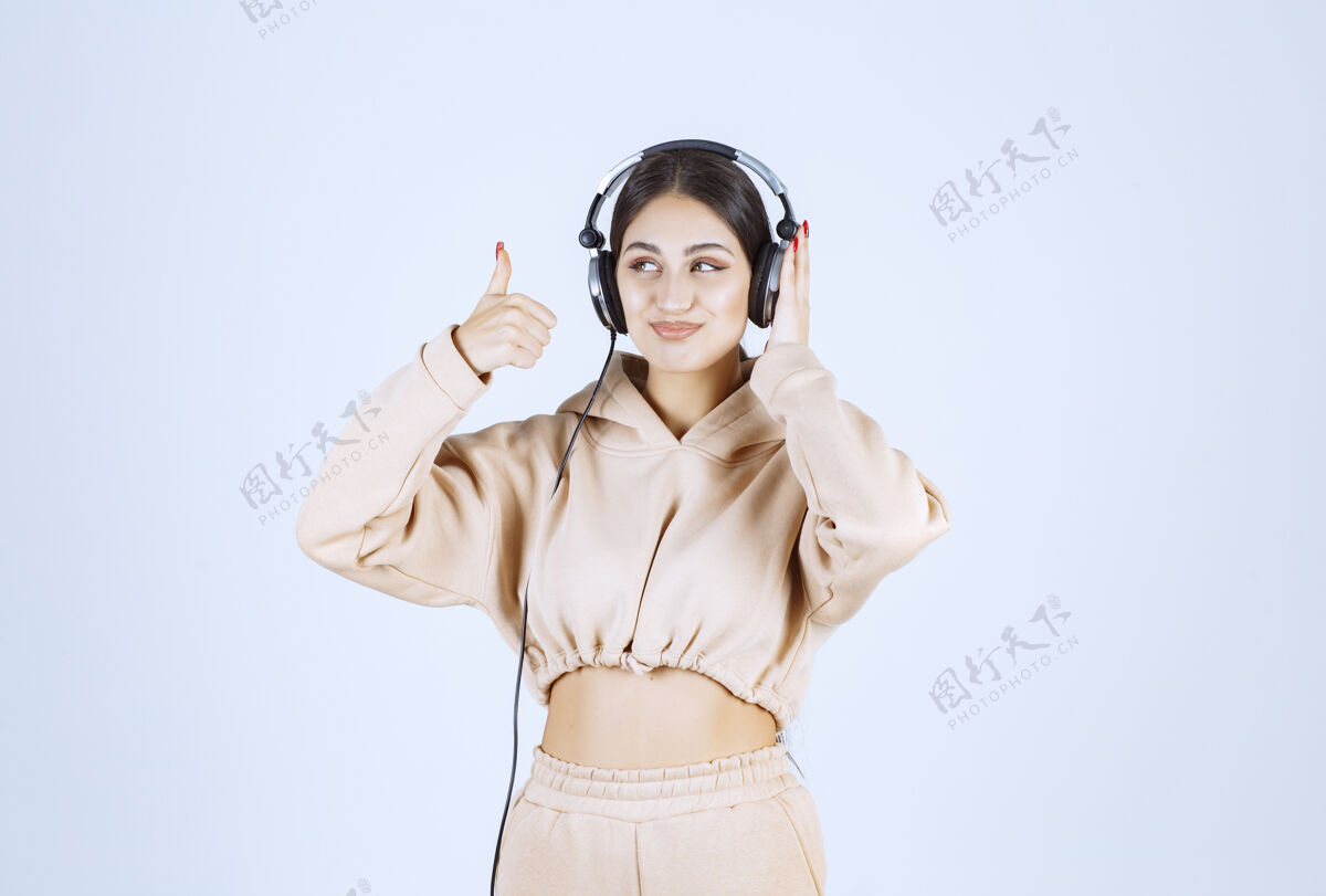 积极听耳机 竖起大拇指的年轻女子成人年轻人类