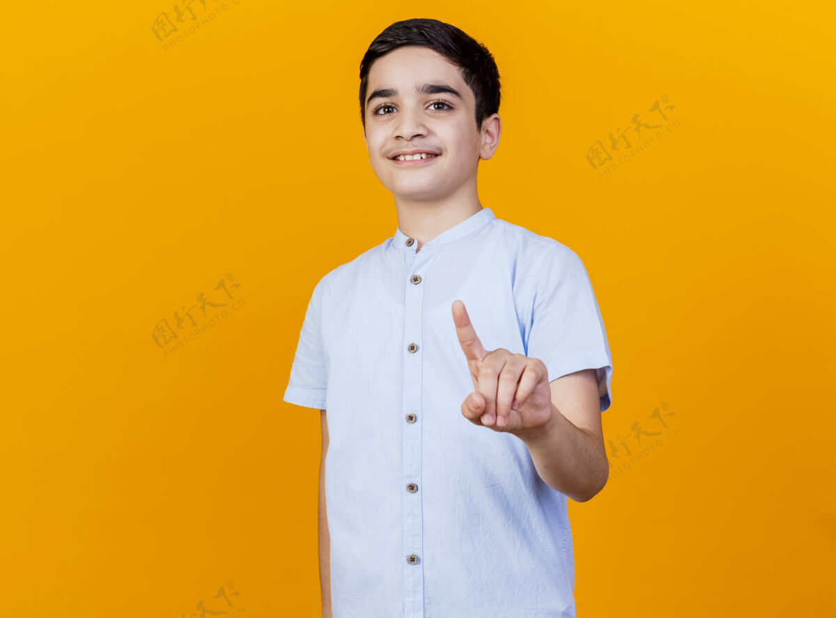 橙色微笑着的年轻白人男孩看着相机 做着保持姿势 在橙色背景上与复制空间隔离手势保持年轻
