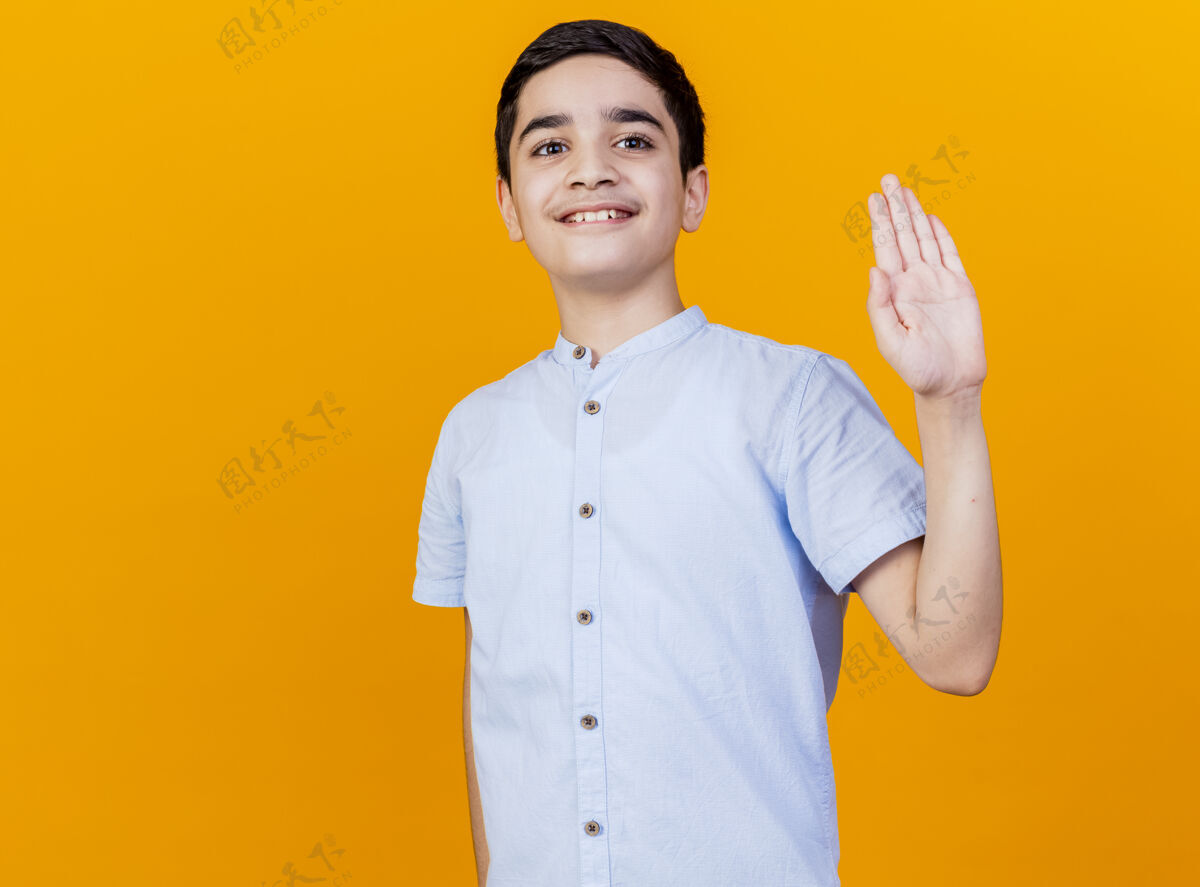 年轻微笑的年轻白人男孩看着相机做嗨手势看着相机孤立的橙色背景与复制空间嗨手势橙色