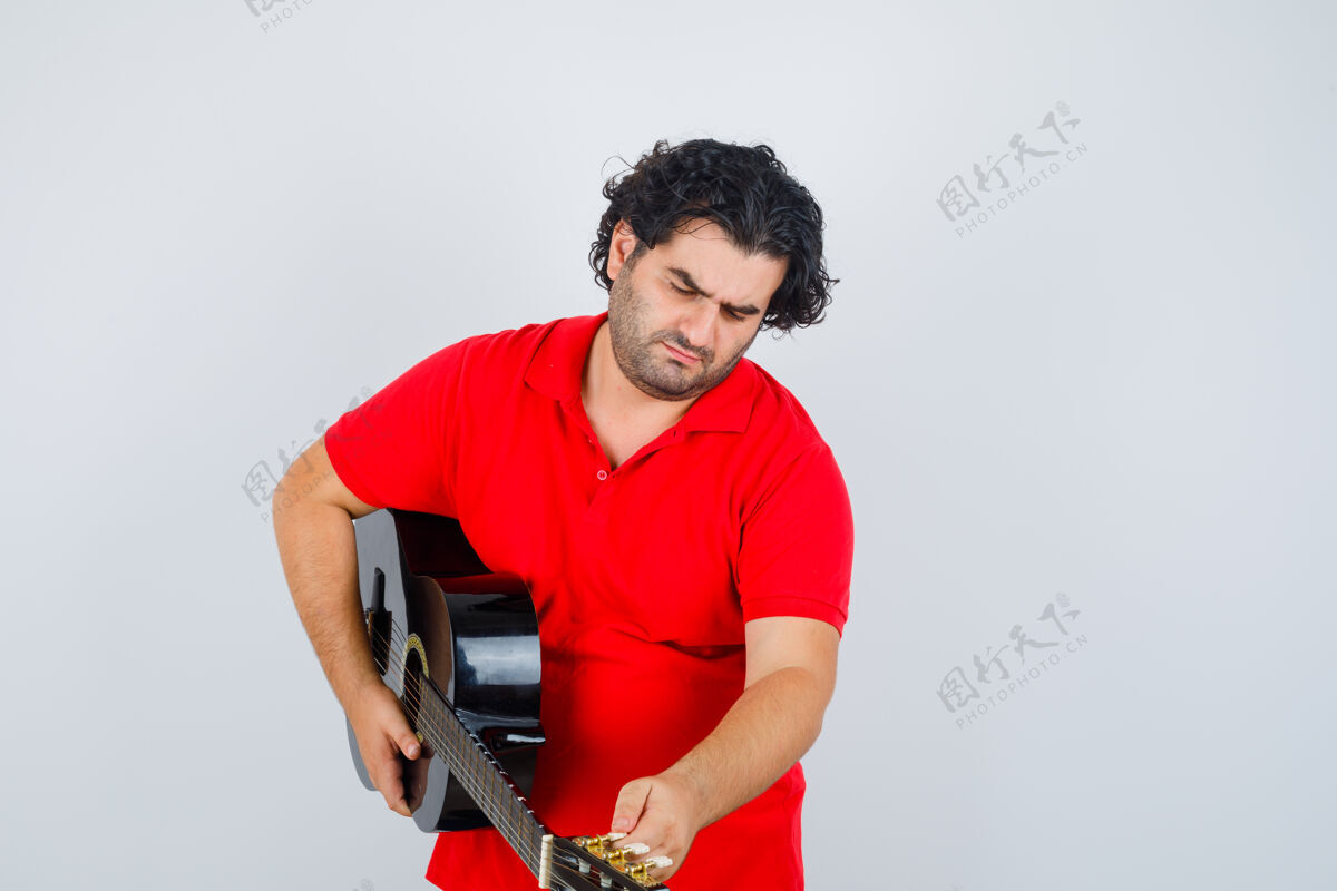 室内帅哥穿着红色t恤弹吉他 看起来很专注 前视图男性训练人