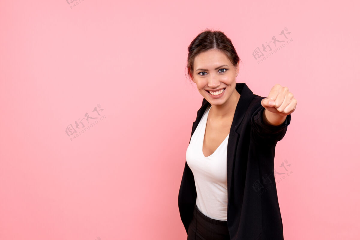 女士正面图：年轻漂亮的女性 穿着粉色背景的深色夹克夹克正面微笑