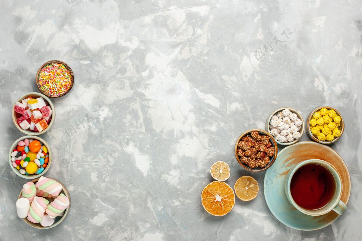 顶视图俯瞰美味的甜度组成糖果和棉花糖与一杯茶在白色的表面庆典杯子含糖