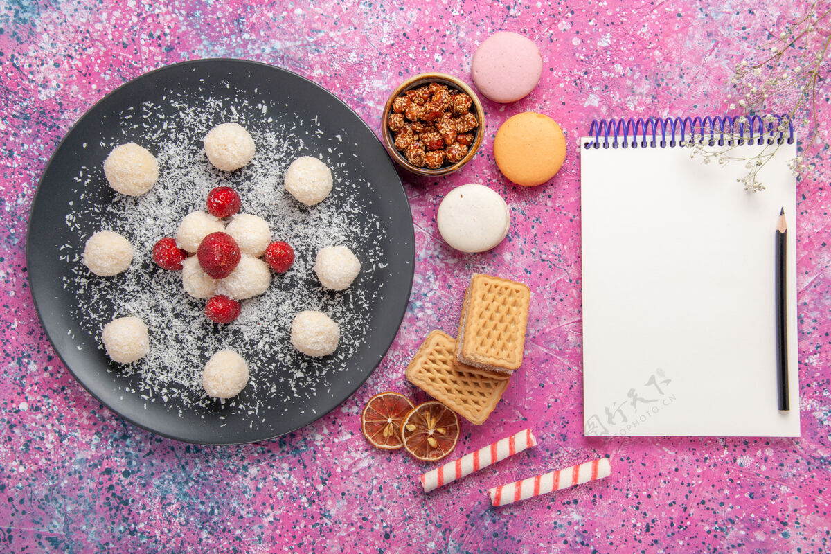 饼干粉红色桌子上美味的椰子糖 甜丸子 法式马卡龙和华夫饼的俯视图生的椰子华夫饼