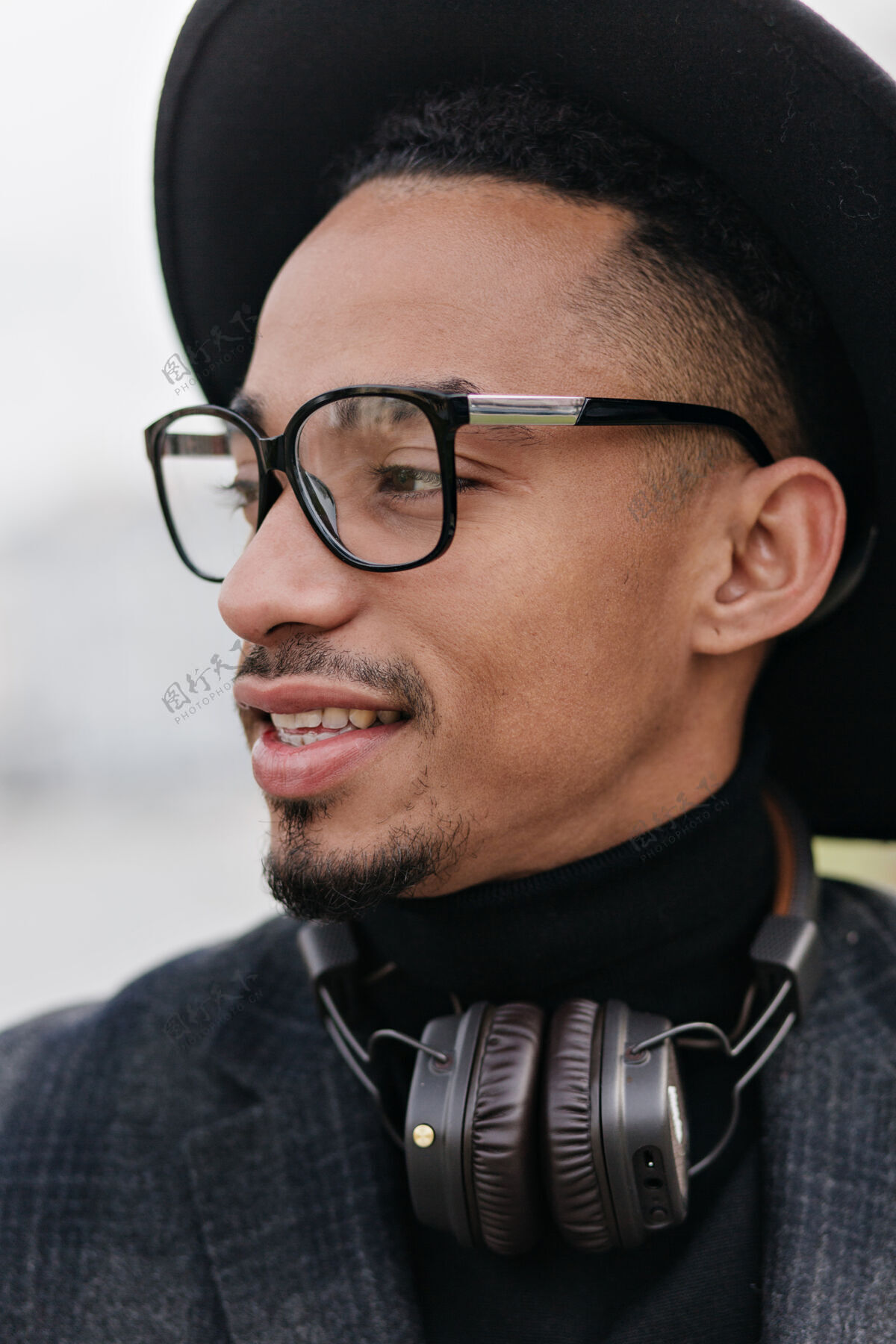 寒冷棕色皮肤的优雅年轻人的特写照片戴着眼镜和耳机的梦幻非洲男模的照片让人毛骨悚然走路年轻享受