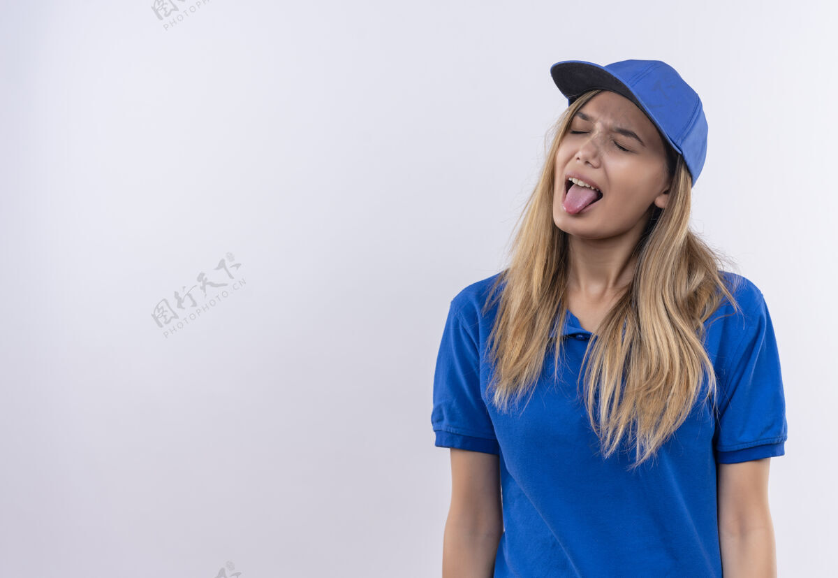 女人闭着眼睛的年轻送货女孩穿着蓝色制服 戴着帽子 舌头被隔离在白色上闭嘴表情舌头