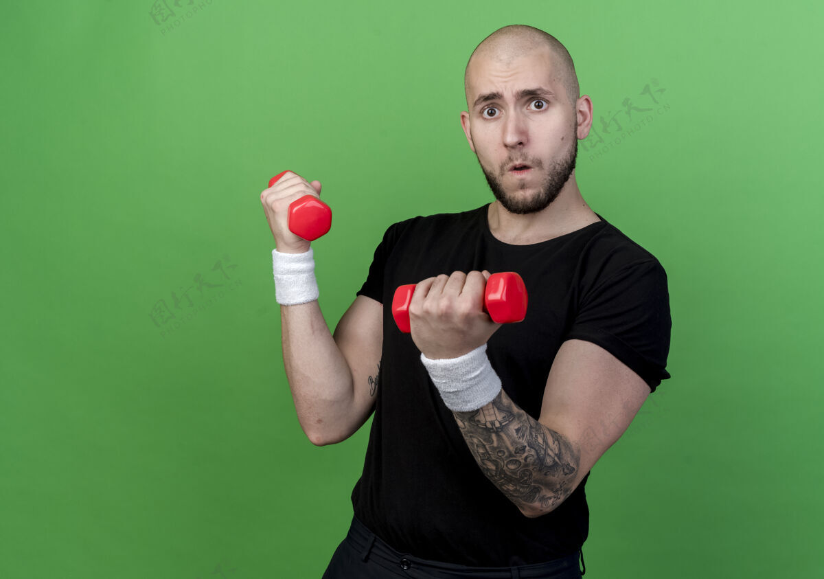 男人紧张的年轻运动型男子戴着手环练习哑铃隔离在绿色哑铃紧张绿色