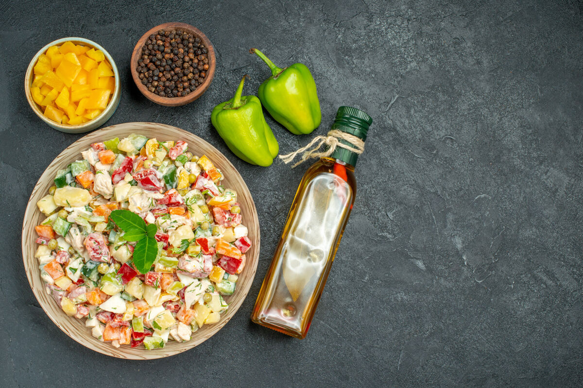 铃铛一碗蔬菜沙拉的顶视图 在黑暗的背景上有一碗蔬菜和胡椒油瓶 还有甜椒沙拉深色肉
