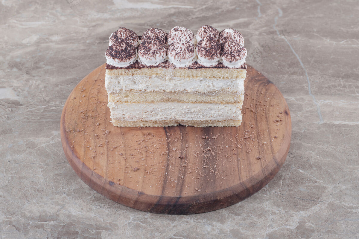 蛋糕奶油和可可粉覆盖在大理石板上的蛋糕片上奶油美味顶部