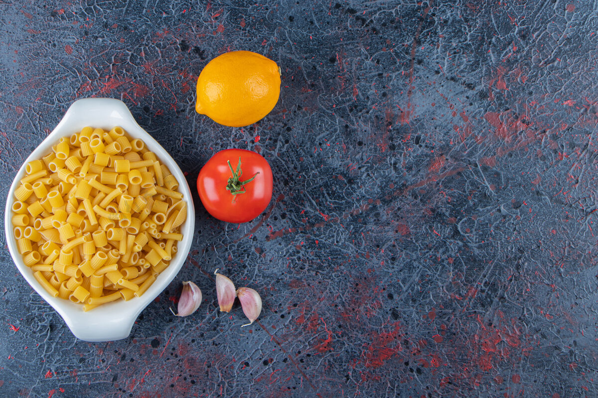 未经料理的一块白色的生面食板 背景是新鲜的红色西红柿和柠檬生的料理晚餐
