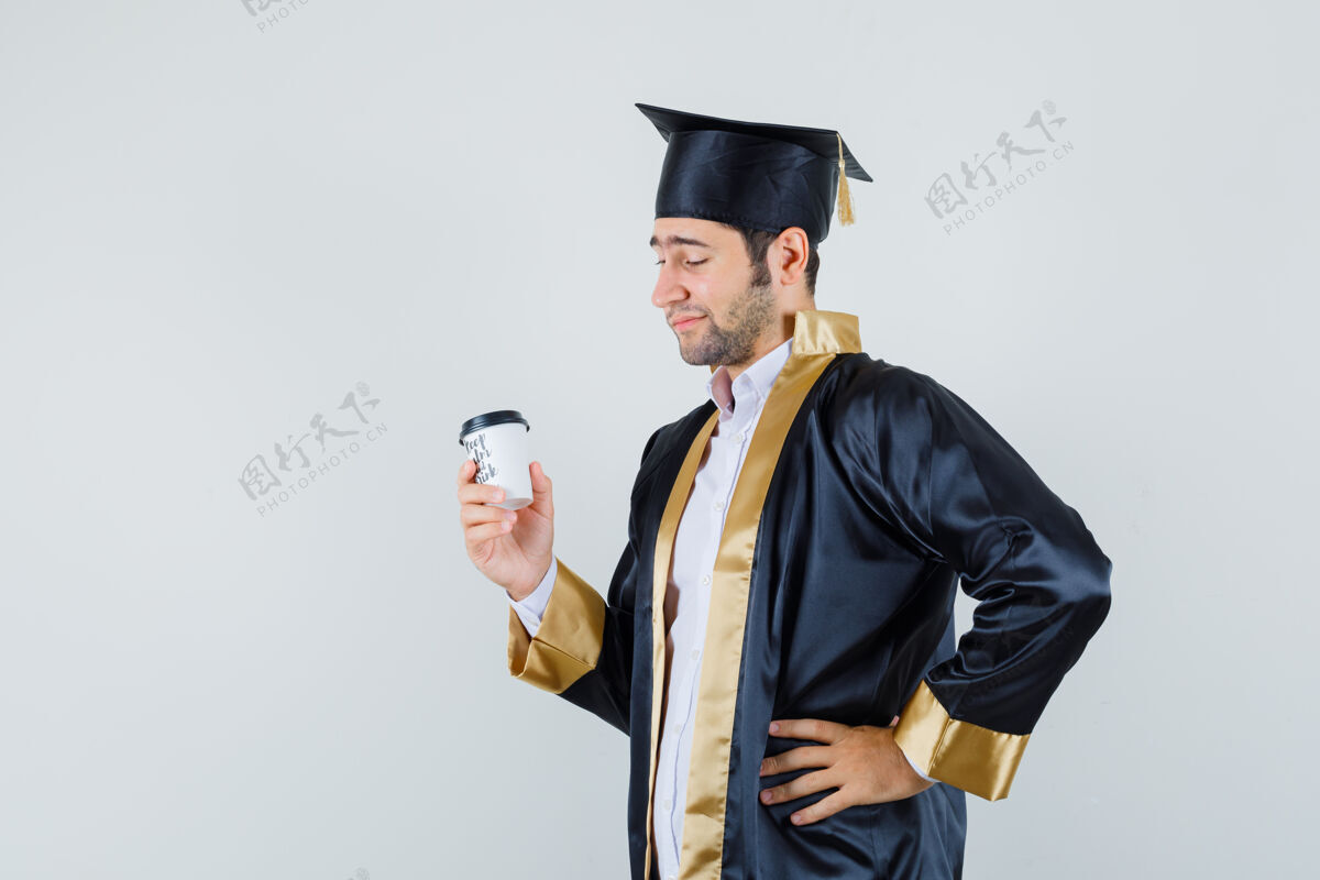 制服年轻的男性穿着研究生制服 看着一杯咖啡 神情沉思 俯视前方手虚拟男孩