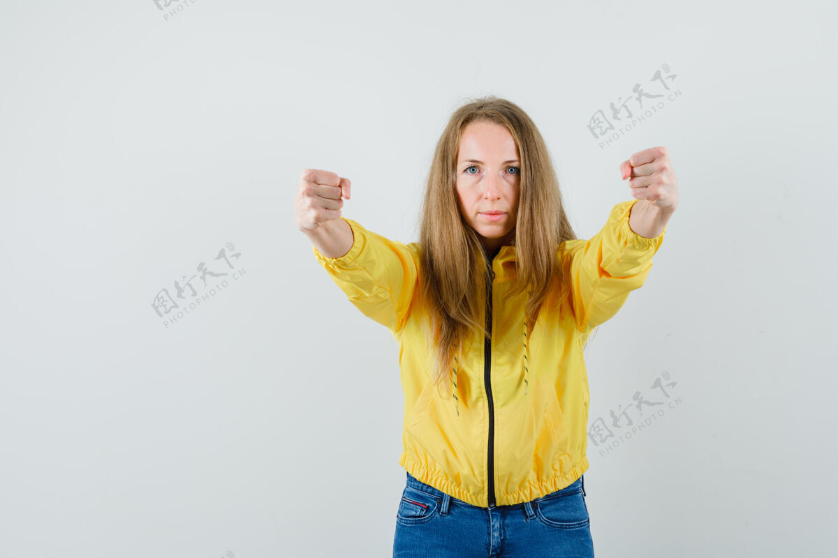 欢呼身穿黄色棒球服和蓝色牛仔裤的年轻女子握紧拳头 表情严肃年轻美女严肃